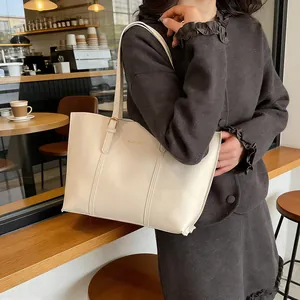 Chic beige tote bag with gold lettering shown on a shoulder in a cafe setting