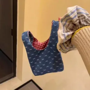 Detail der Mini-Tragetasche aus Denim mit weißem Schleifenmuster und Karofutter