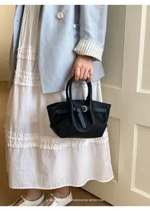 Detail of black woven handbag featuring a silver buckle strap and retro minimalist texture