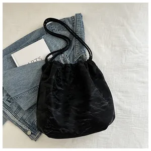 Detail of black drawstring bucket bag with shiny pleated texture on white background