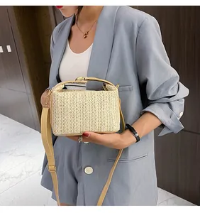 Detail view of woven straw crossbody bag with PU leather straps shown on a model