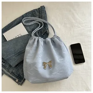 Detail of light blue pleated bucket bag with silver bow accent and drawstring design