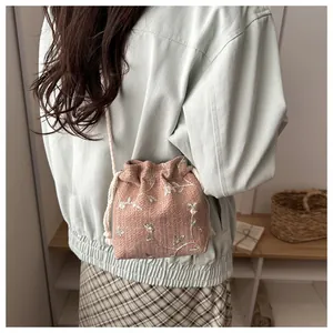 Detail einer rosa gewebten Beuteltasche mit Blumenstickerei und Kordelzug-Schultergurt