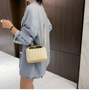 Detail of a beige woven straw crossbody bag with PU leather trim on a model