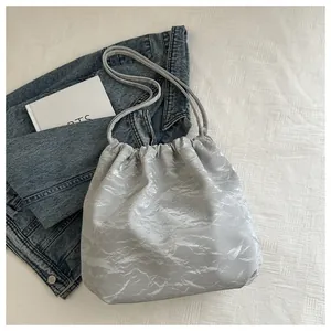 Detail of grey bucket bag with silk sheen finish and silver marble pleated texture