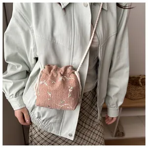 Nahaufnahme der rosa geflochtenen Beuteltasche mit Blumenstickerei und Kordelzug
