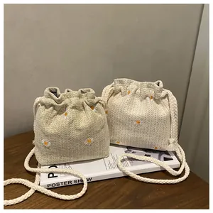 Detail of woven straw bucket bag with daisy embroidery and cotton rope drawstring