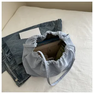 Spacious interior of light blue pleated shoulder bag holding books and an umbrella