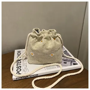 Detail of drawstring bucket bag with daisy embroidery and braided cotton rope strap