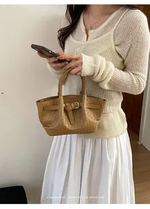 Close-up of a tan woven shoulder bag featuring a knotted strap with a silver metal buckle