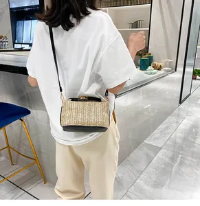 Detail view of woven straw crossbody bag with black leather trim and gold lock on model