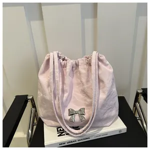 Detail of light pink drawstring shoulder bag with crinkled texture and silver bow detail