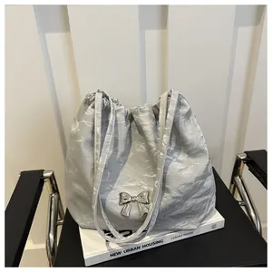 Detail view of silver bucket bag with metallic crinkle texture and bow buckle