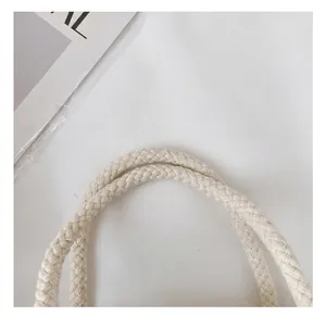 Detailopname van de crèmekleurige gevlochten katoenen handvatten op een canvas draagtas