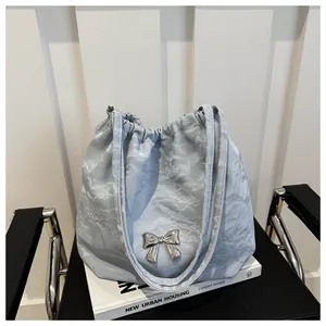 Detail of light blue pleated bucket bag with metallic silver bow and drawstring