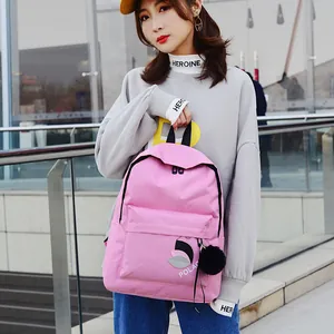 Pink nylon backpack detail with POLAC text print and a soft black pompom charm