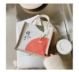 Detail of canvas tote bag featuring an orange graphic print and rustic hemp rope handles