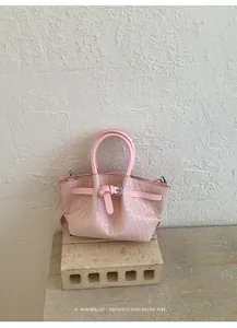 Close-up of pink woven bucket bag with retro buckle detail on stone platform