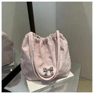 Close-up of pale pink pleated tote bag featuring a metallic silver bow ornament