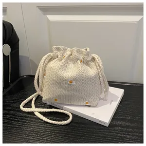 Dettaglio ricamo a margherita su borsa a secchiello in tessuto crema con coulisse e corda