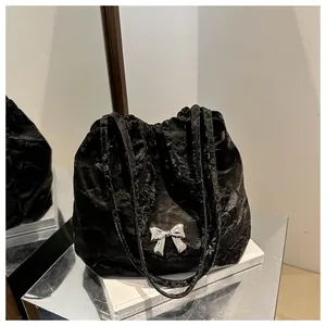 Detail of black pleated shoulder bag featuring a silver metal bow and drawstring closure