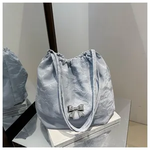 Close-up of light blue pleated bucket bag featuring a metallic silver bow and drawstring