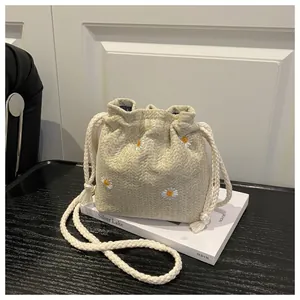 Detailed macro view of beige bucket bag with white daisy embroidery and drawstring