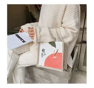 Close-up of a Japanese style canvas tote bag with orange illustration and cord handle