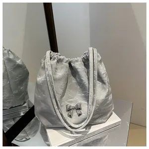 Macro detail of silver pleated tote bag with metallic bow and crinkle texture
