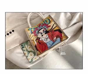 Draufsicht der Canvas-Handtasche mit Cartoon-Grafik und Handyhülle zum Größenvergleich