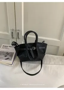 Detail view of black woven texture handbag with decorative buckle and dual handles