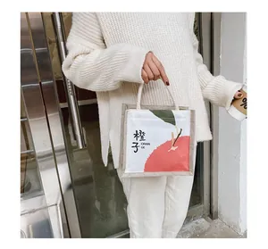 Detail of canvas tote bag with orange print and natural jute trim held by a model