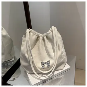 Detailed view of cream bucket bag with crinkled texture and silver metallic bow buckle