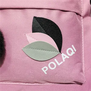 Close-up of pink nylon backpack featuring leaf leather patches and POLAQI logo detail