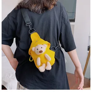 Detail of yellow canvas chest bag featuring a 3D plush bear and adjustable black strap