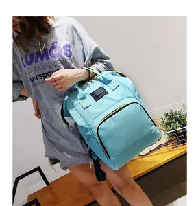 Detail view of large capacity light blue diaper backpack worn by a model in a cozy room