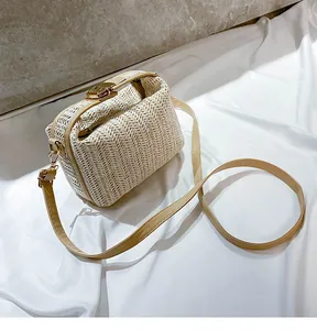 Detail shot of beige straw woven crossbody bag with metallic clasp and leather strap