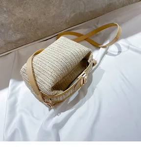 Close-up of beige V-shaped straw weave handbag with golden metal lock and leather strap