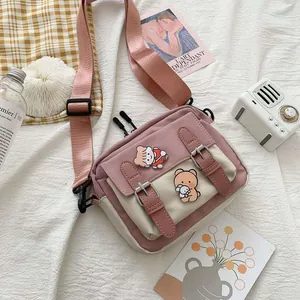 Detail of pink and beige canvas crossbody bag with adjustable strap and cute cartoon badges