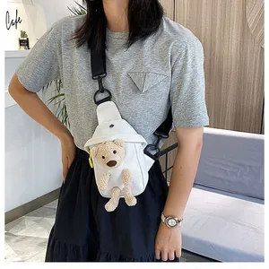 Close-up of a white canvas chest bag featuring a 3D plush bear and black strap