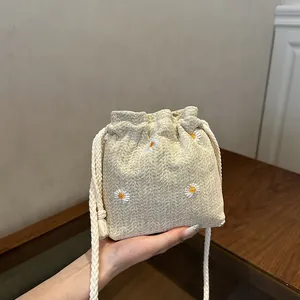 Minimalist beige linen bucket bag with yellow daisy embroidery and drawstring closure