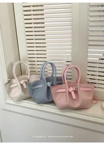 Detailed close-up of woven bucket bags in off-white, light blue, and pink with metal buckles