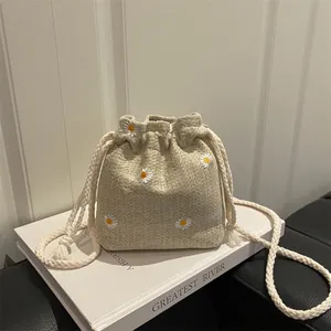 Minimalist beige bucket bag with daisy embroidery and woven rope shoulder strap