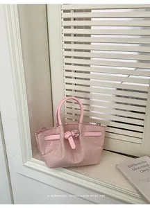 Detail of pink woven leather bucket bag with decorative buckle and metal strap loops