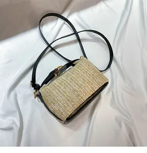 Close-up of woven straw texture and black leather stitching on a mini crossbody bag