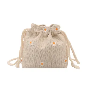 Minimalist drawstring bucket bag with daisy embroidery and herringbone fabric texture