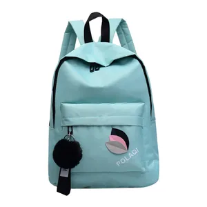 Detail of light blue nylon backpack with leaf pattern and plush pompom keychain