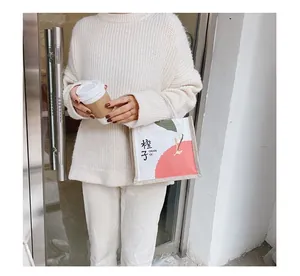 Close-up of a white canvas tote bag featuring an orange illustration and a model holding coffee