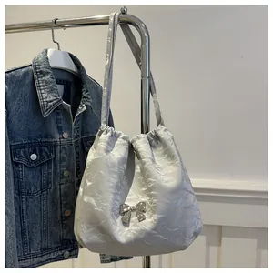 Detail of silver metallic drawstring bucket bag with bow ornament and pleated texture