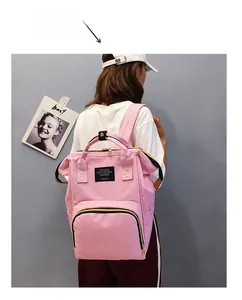 Rear view of pink canvas diaper backpack with contrast yellow zippers and dual handles